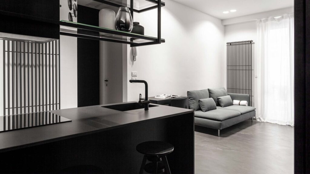 Cucina e living di un miniappartamento nei toni di nero e grigio