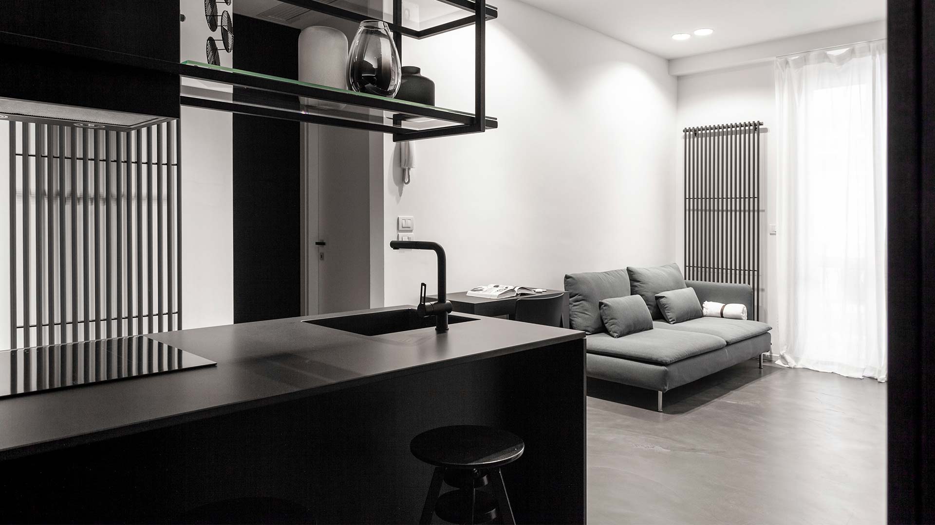 Cucina e living di un miniappartamento nei toni di nero e grigio