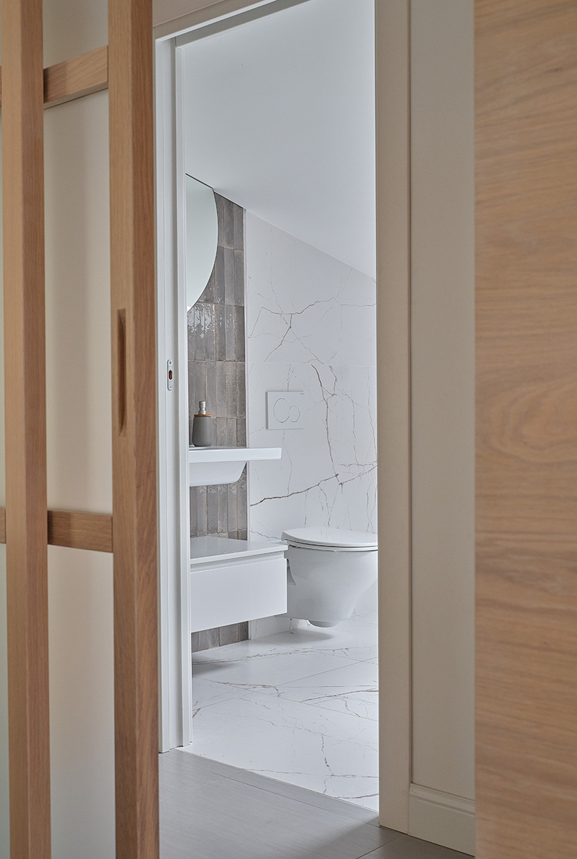 Porta scorrevole in rovere sbiancato che svela il bagno di servizio